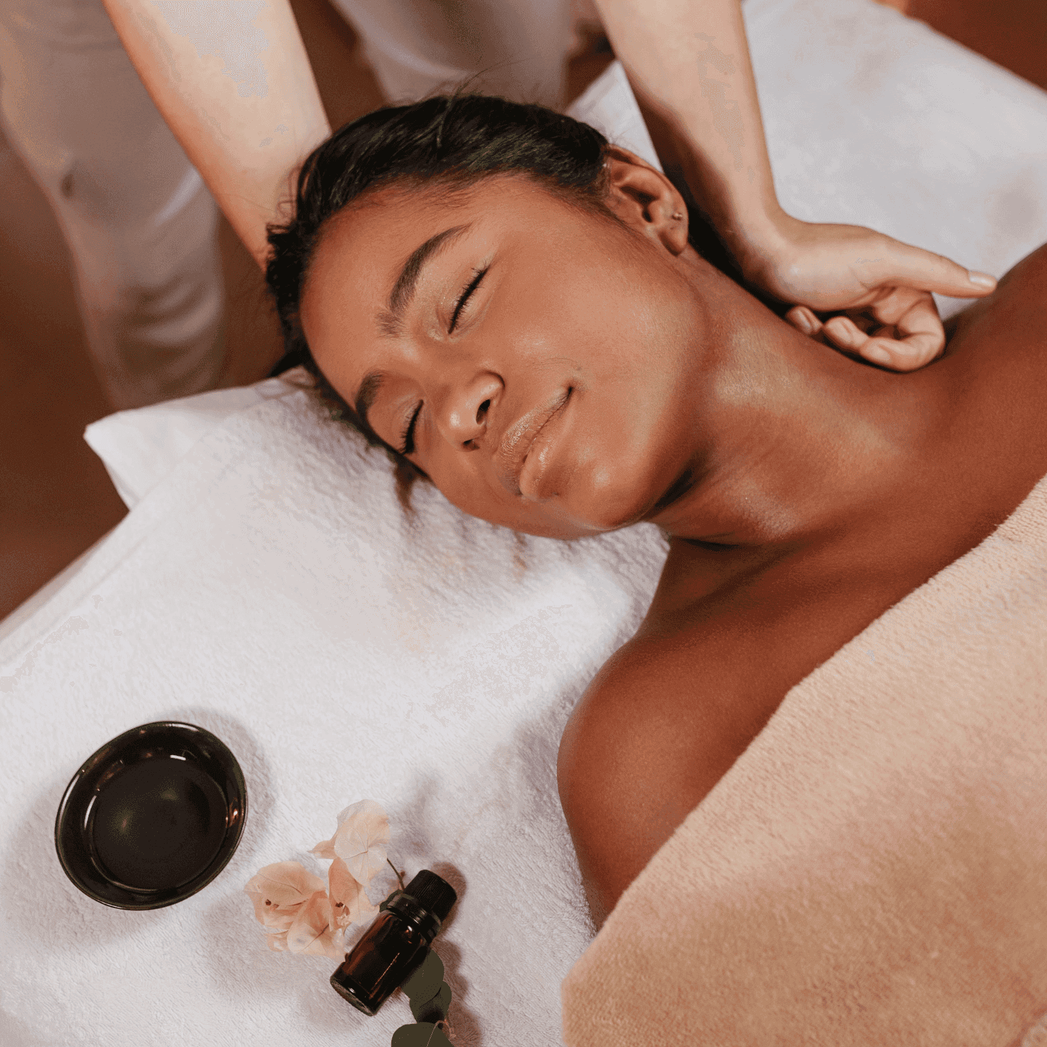 Woman receiving a relaxing neck massage at a spa, surrounded by oils and flowers.